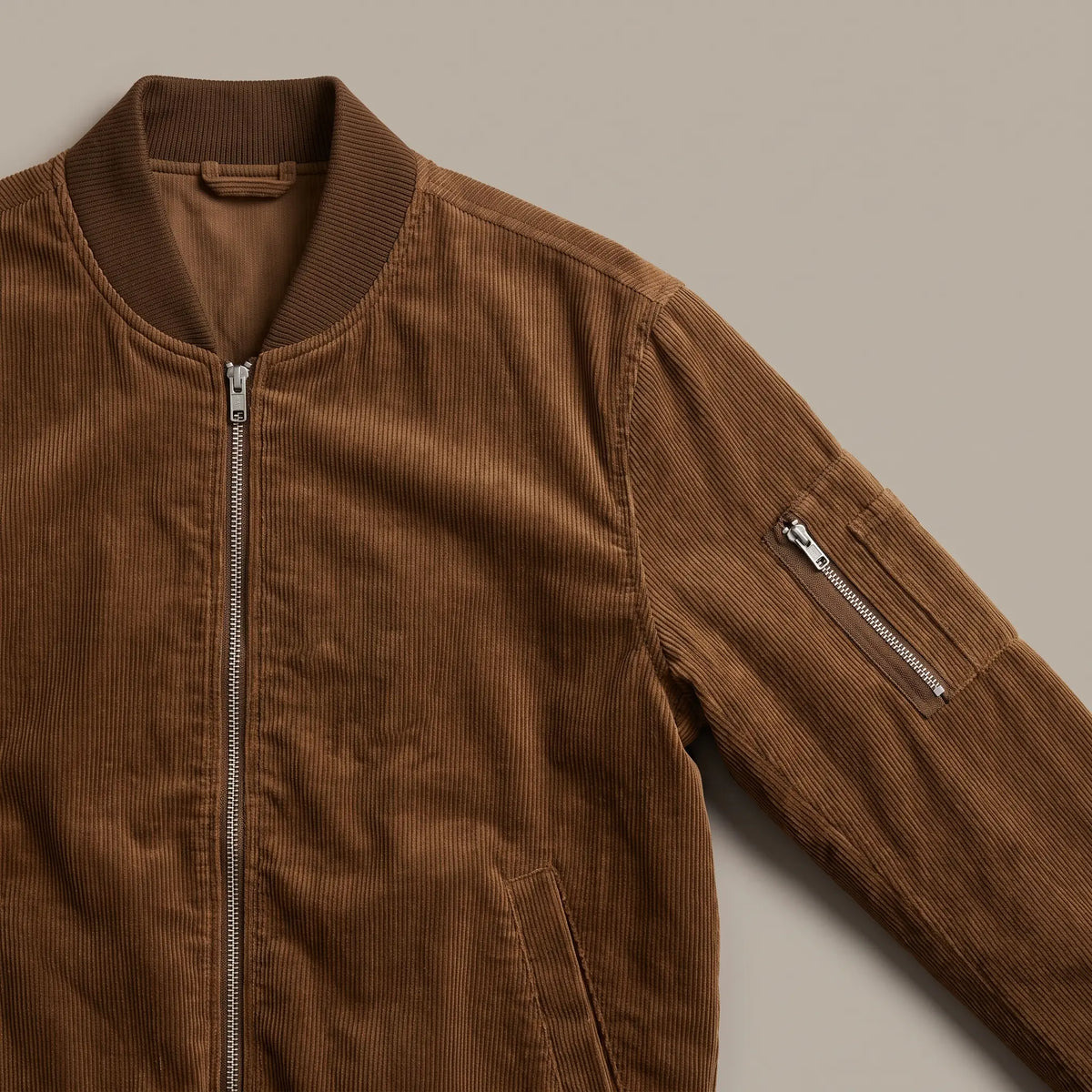 Close up of the ribbed collar and zipped sleeve pocket on the brown snap pocket bomber