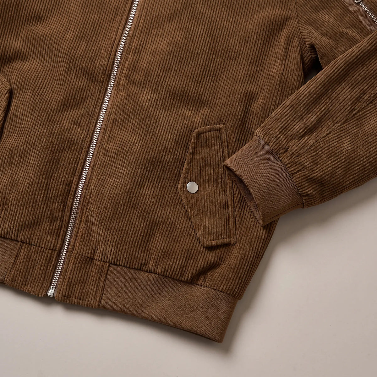 Close up of the snap-flap pocket, ribbed cuff and hem on the brown snap pocket bomber