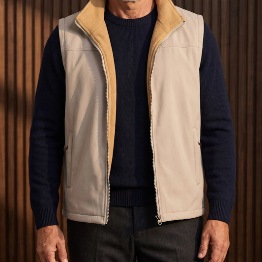 Men's beige softshell vest with camel fleece lining, worn open over a navy sweater