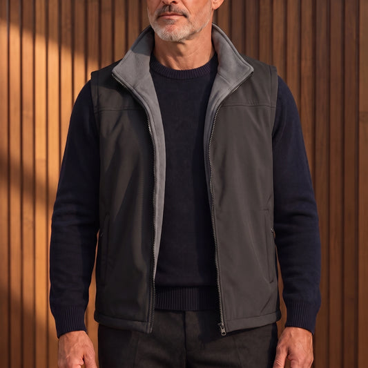Men's black softshell vest with grey fleece lining, worn open over a navy sweater