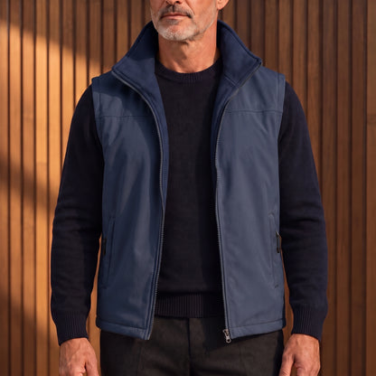 Men's navy blue softshell fleece vest worn open over a navy sweater