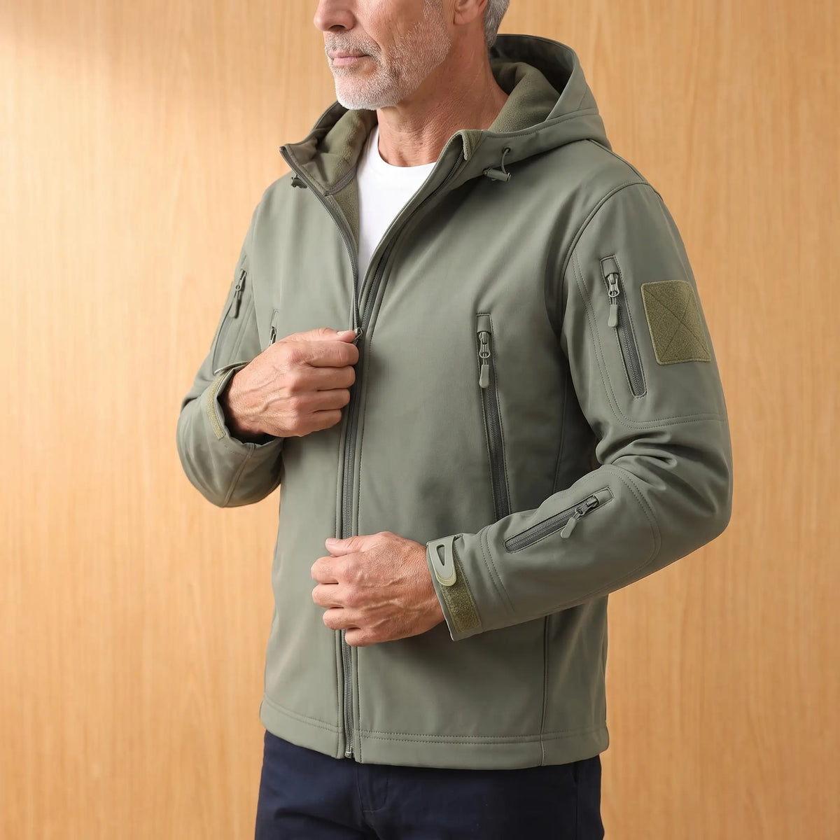 Man zipping up a green softshell hooded jacket