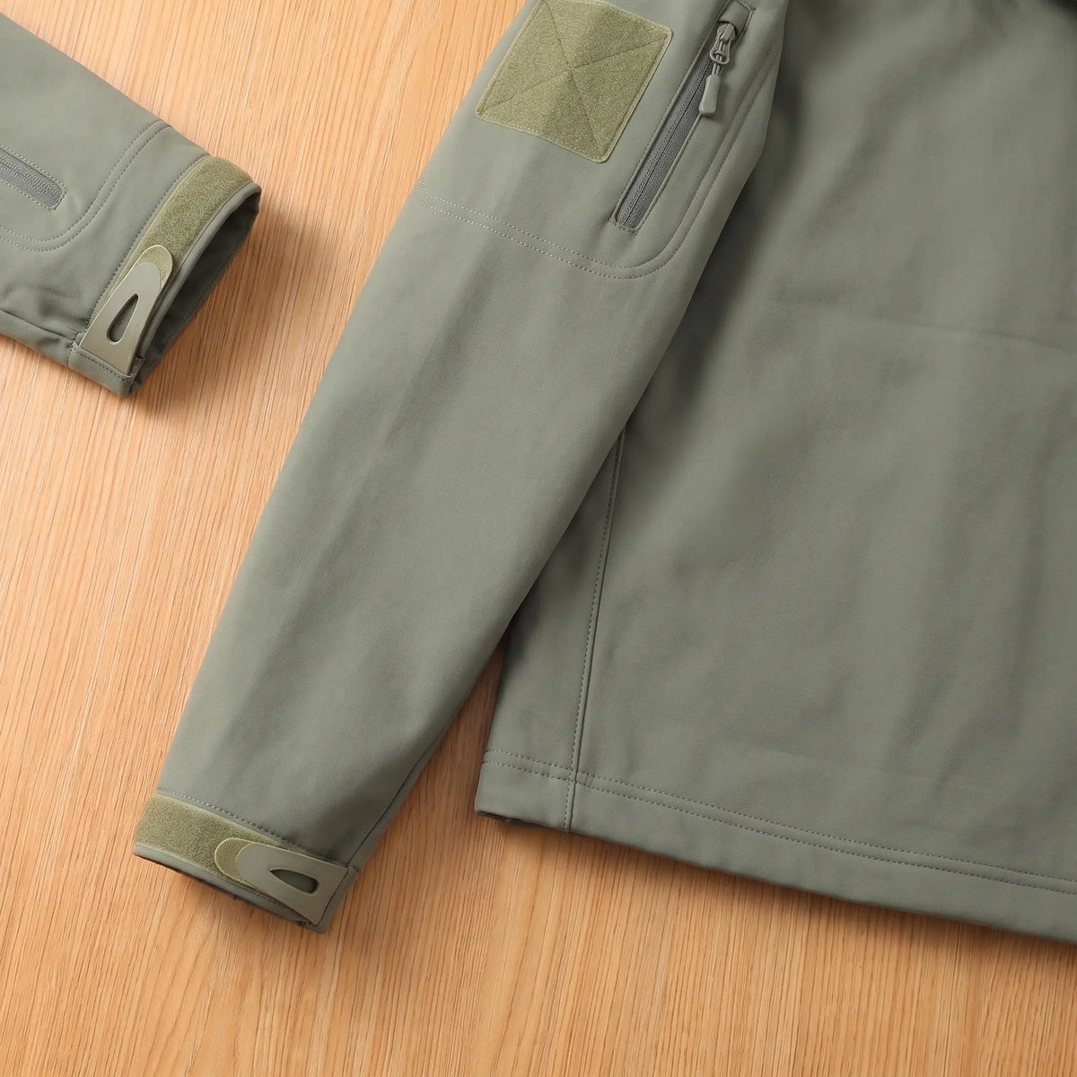 Close-up of the green softshell jacket sleeve patch, sleeve pocket and cuff tab