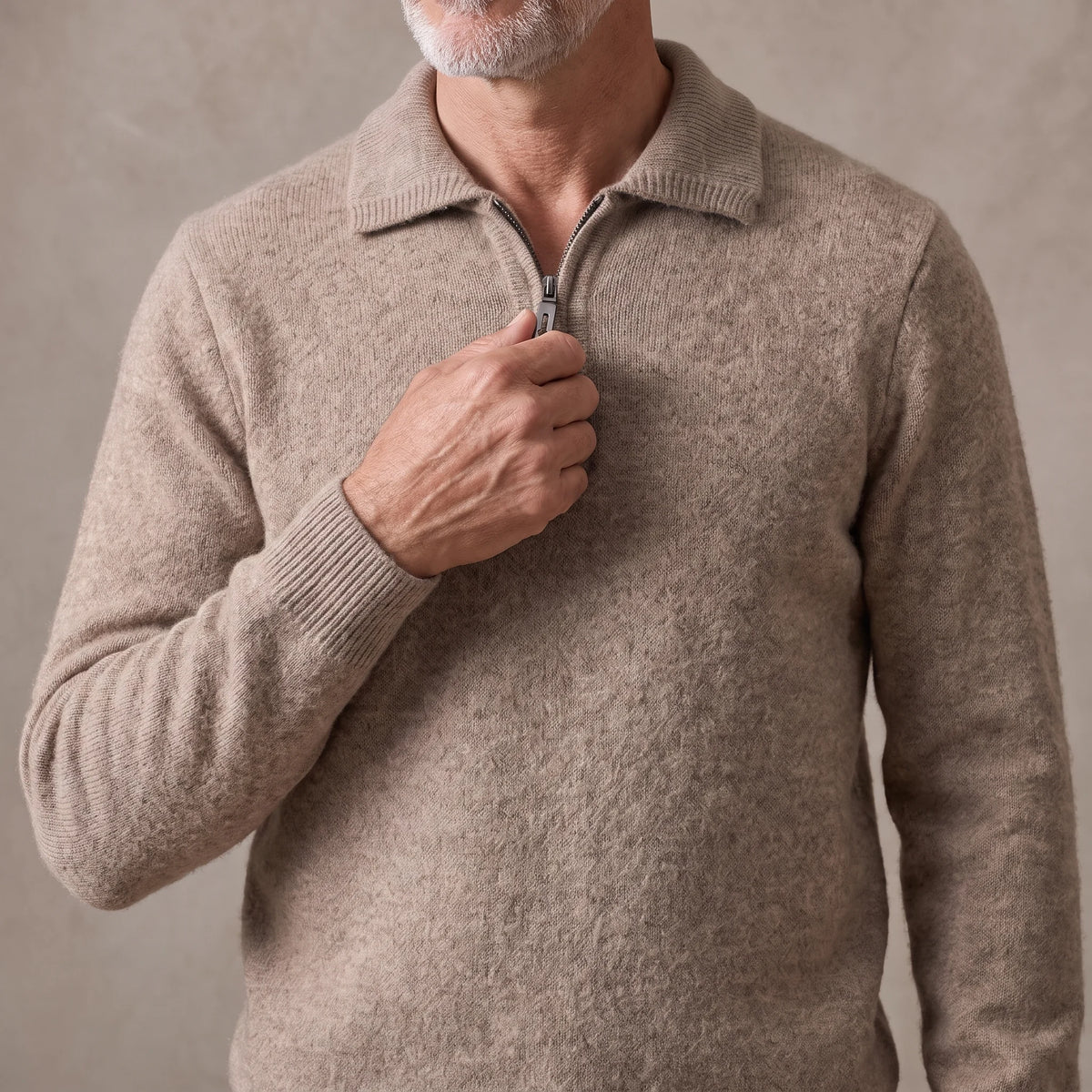 Man zipping up the quarter-zip on the tan spread collar knit sweater