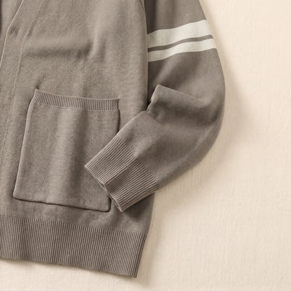Close-up of men's khaki knit cardigan patch pocket, ribbed cuff and sleeve stripes