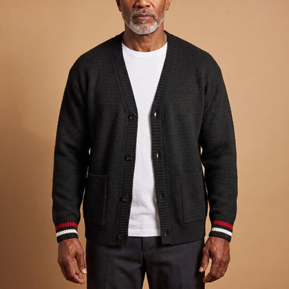 Man wearing the Stripe Cuff Cardigan in black, a textured knit V-neck cardigan with red and white striped cuffs, worn open over a white tee