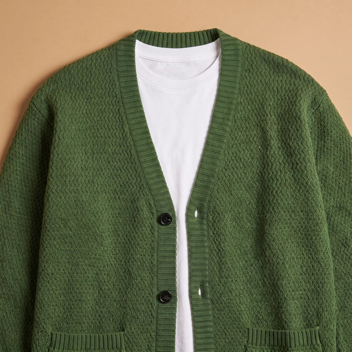 Close-up of the Stripe Cuff Cardigan in green showing the ribbed V-neck, button band and honeycomb knit texture
