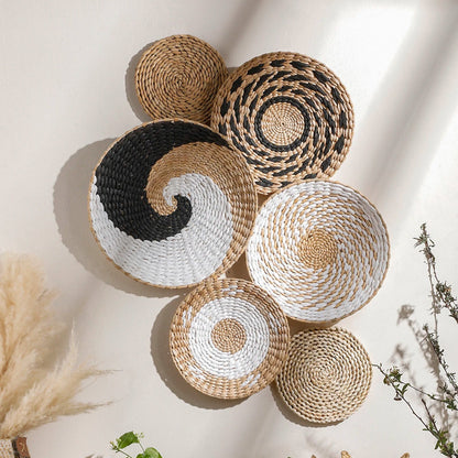 Woven baskets of various sizes and colors on a light wall with plants and decor.