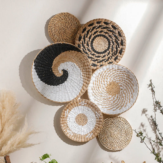Woven baskets of various sizes and colors on a light wall with plants and decor.