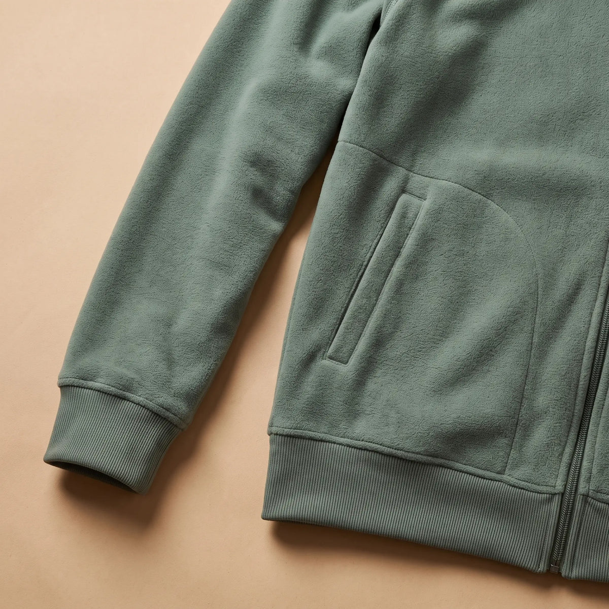 Close detail of TALL COLLAR FLEECE showing the ribbed cuff, slash pocket and hem