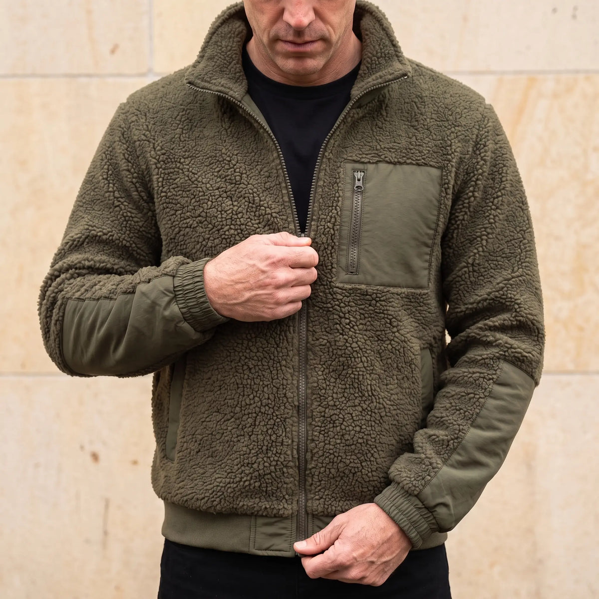 Man zipping up the TEDDY FLEECE JACKET in army green