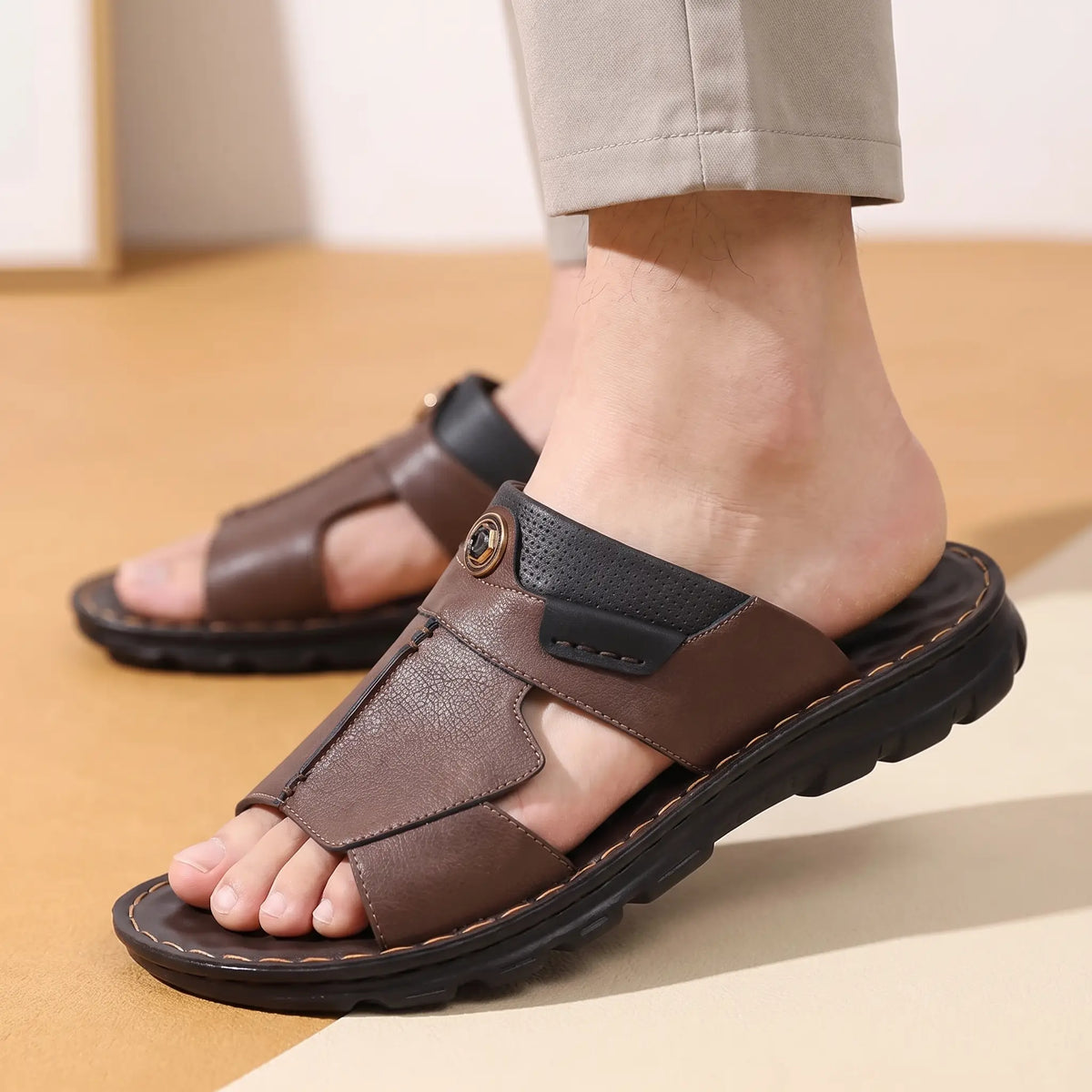 Man sliding his foot into a brown open toe leather slide indoors