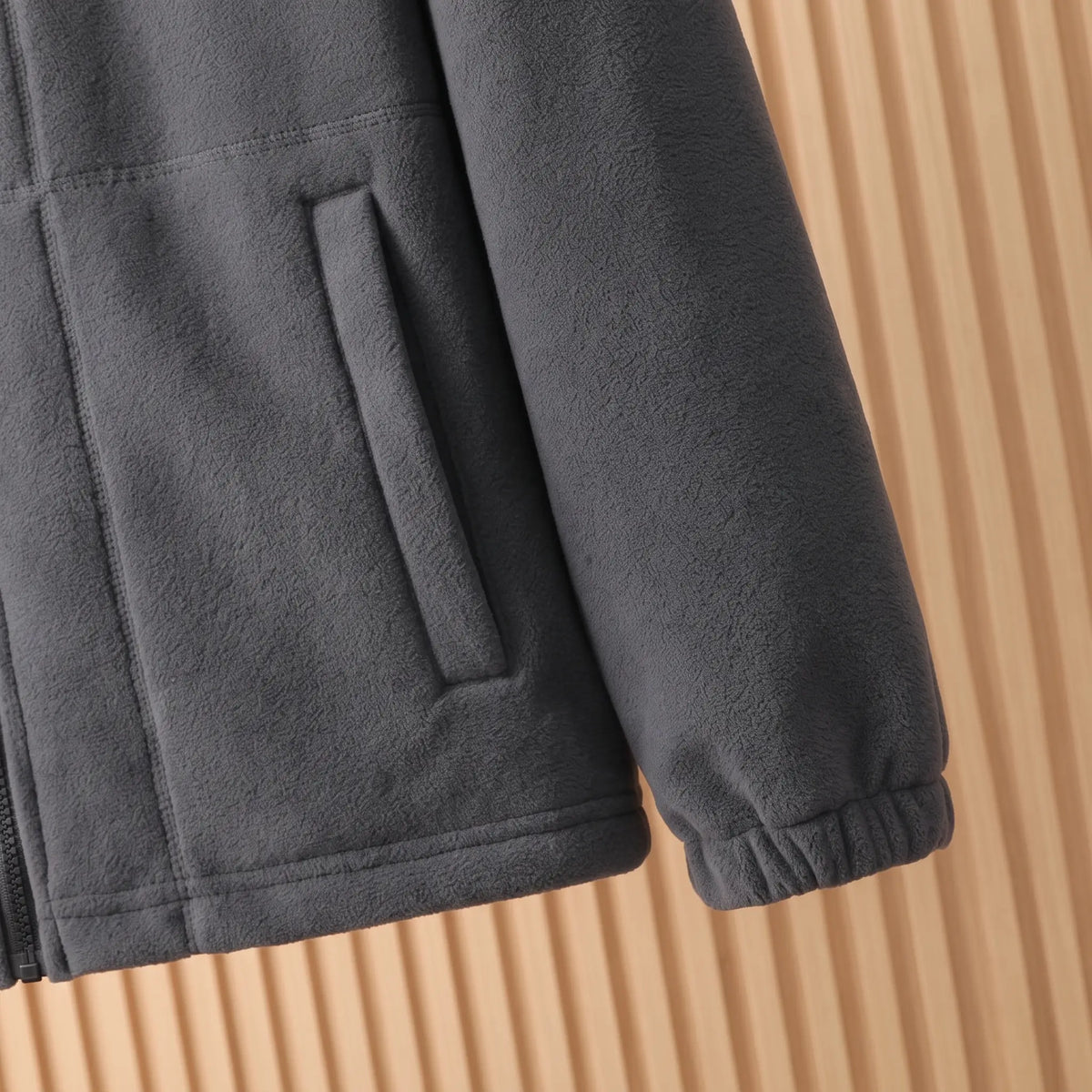 THICK POLAR FLEECE cuff and hem close-up - elasticated cuff, slanted welt pocket and straight hem on the grey jacket