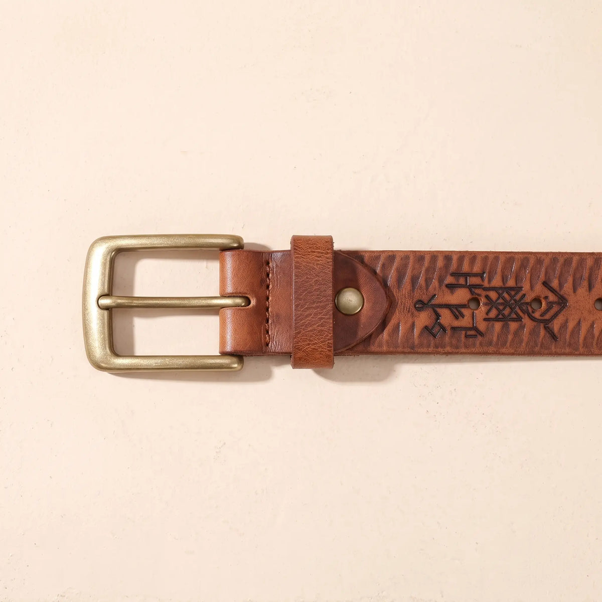 Close up of the THICK STAMPED BELT antique brass single prong buckle, keeper loop and stamped strap