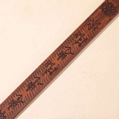 Close up of the THICK STAMPED BELT cowhide strap showing the pressed tribal pattern and punched holes