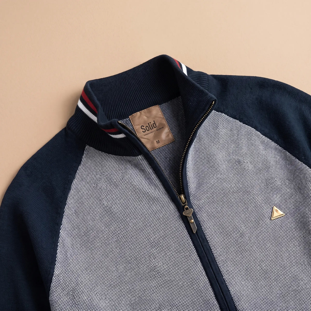 Close-up of men's zip knit cardigan stand collar with red and white tipping and metal zip