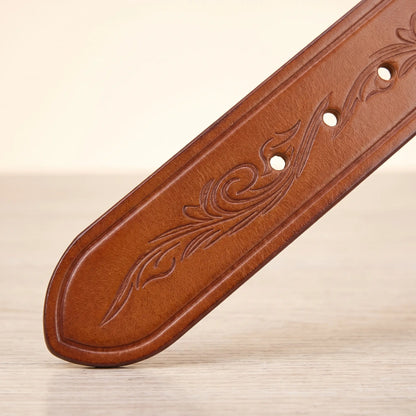 Close up of the embossed scroll tooling, burnished edge and punched holes on the tan tooled cowhide belt