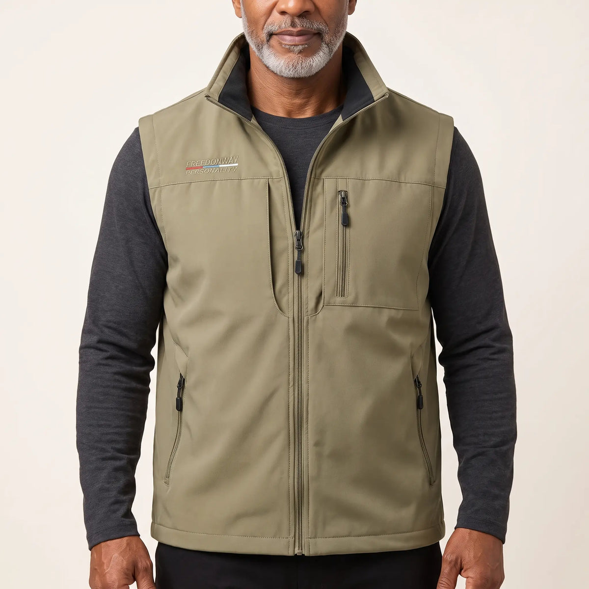 Man wearing the khaki zip-front outdoor vest over a charcoal long-sleeve top