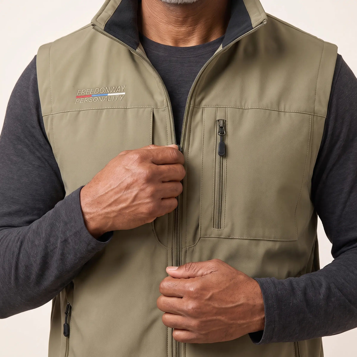 Man zipping up the front of the khaki outdoor vest