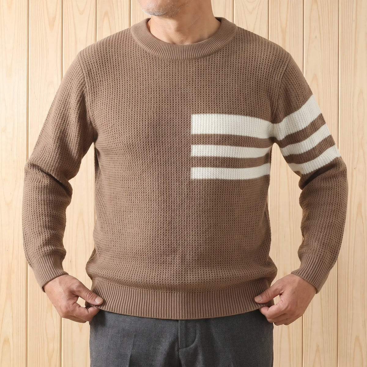 Man wearing the TRIPLE STRIPE SWEATER in brown with charcoal trousers