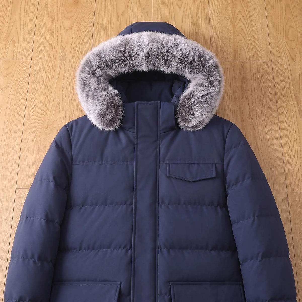 Flat lay of the fur trimmed hood and chest pocket on a navy blue warm longline parka for men