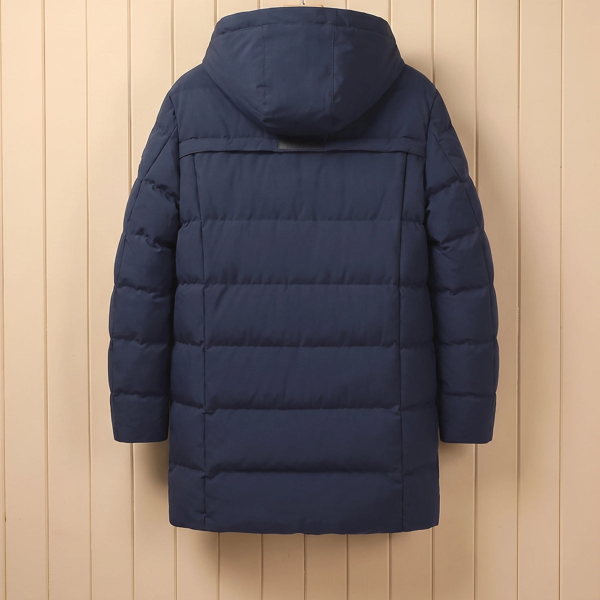 Back view of navy quilted winter coat with hood on a wooden hanger