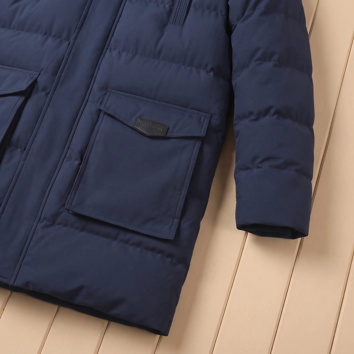 Close-up of navy quilted coat large flap pocket and sleeve cuff