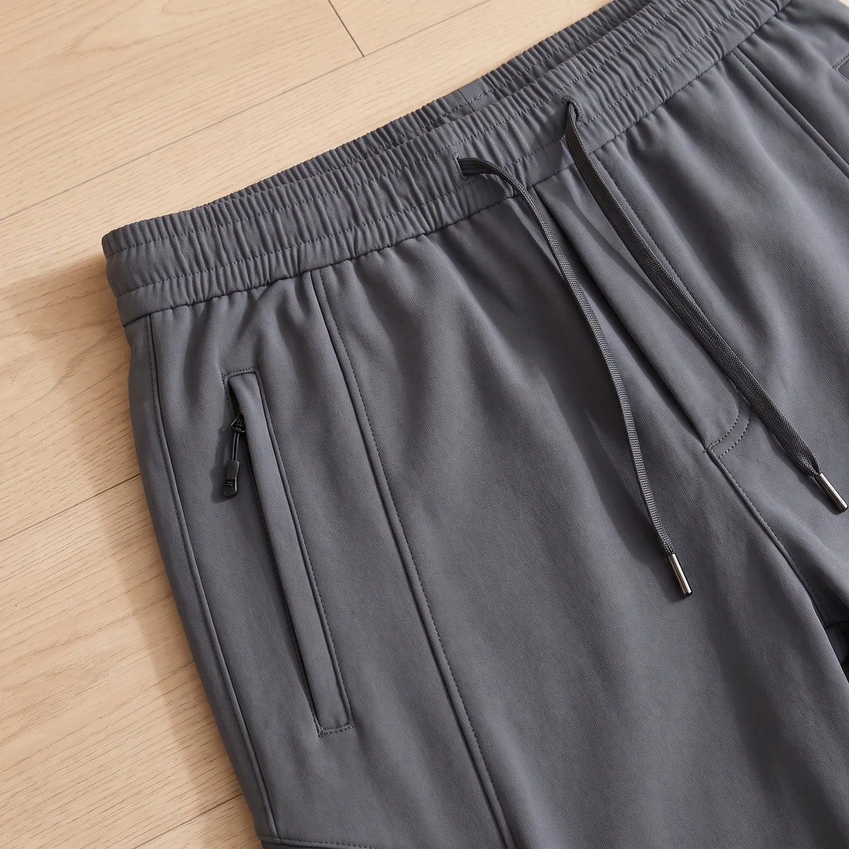 Close up of the WARM TRAIL JOGGERS elastic drawcord waist and zip pocket