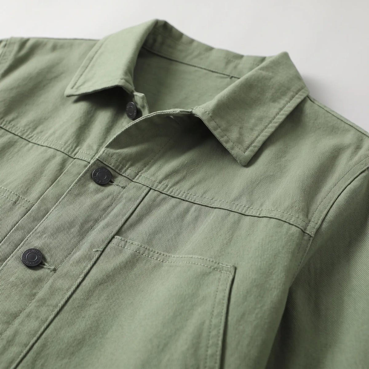 Close up of the collar, chest yoke seam and welt pocket on the green washed chore jacket