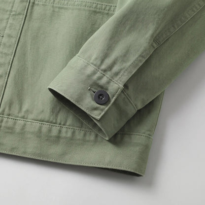 Close up of the buttoned cuff and straight hem on the green washed chore jacket