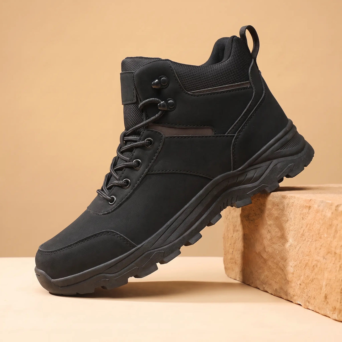 Black waterproof hiking boots for men, high-top lace-up boot on a sandstone block