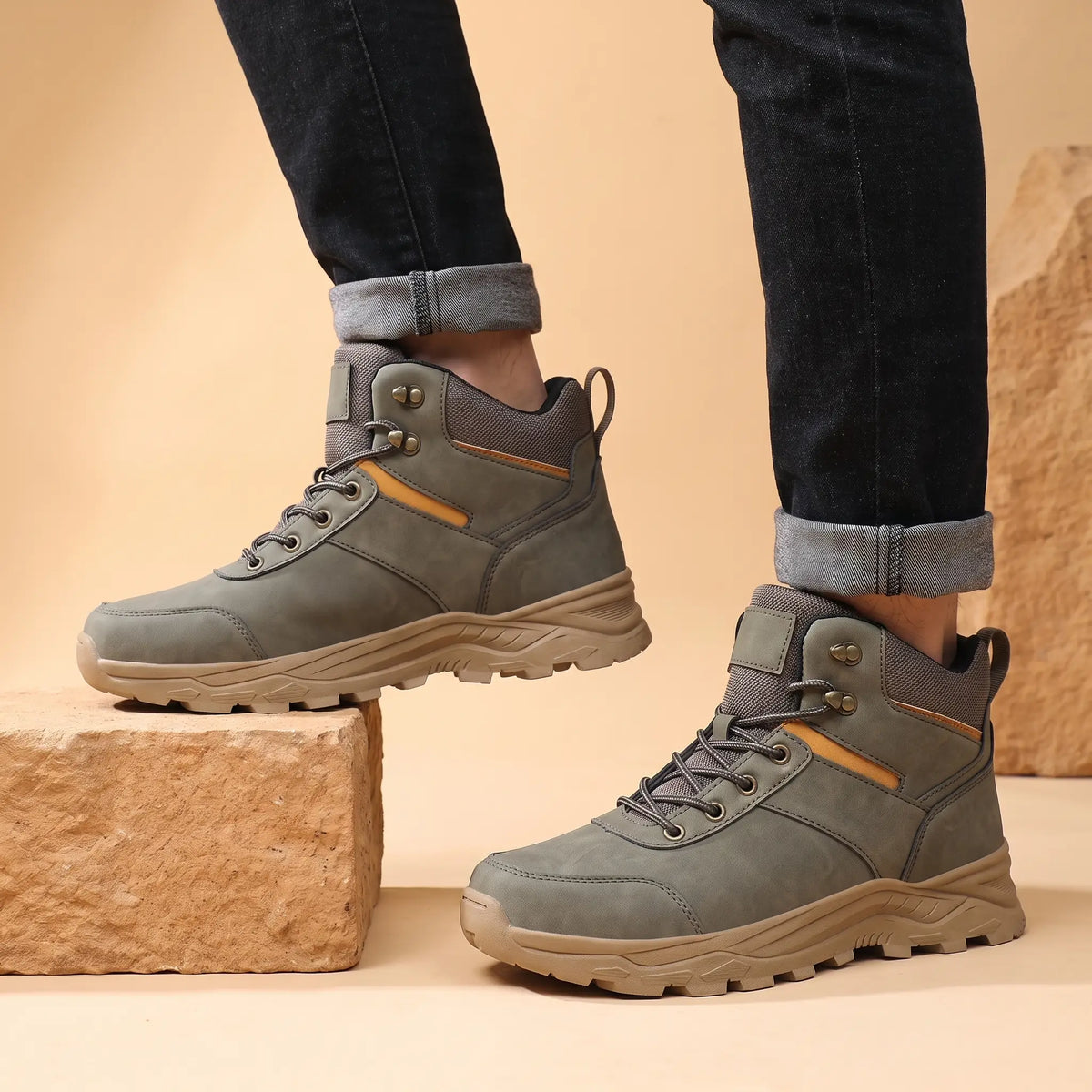 Man wearing green waterproof hiking boots with dark jeans on a sandstone step