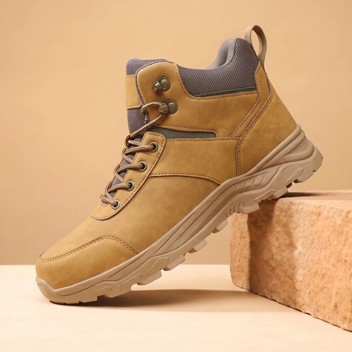 Khaki waterproof hiking boots for men, high-top lace-up boot on a sandstone block