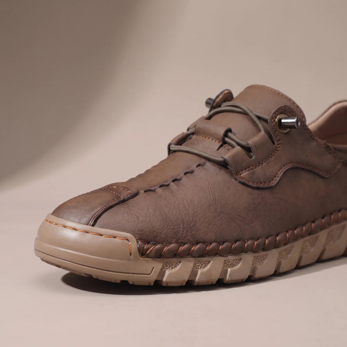 Close-up of the whipstitched moc toe and lacing on the brown casual shoe