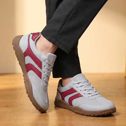 Man wearing the Wide Toe Trail Sneakers with charcoal trousers, ankles crossed