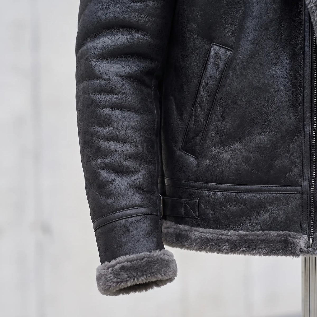 Close detail of WIDE COLLAR JACKET showing the shearling-trimmed cuff, welt pocket and hem