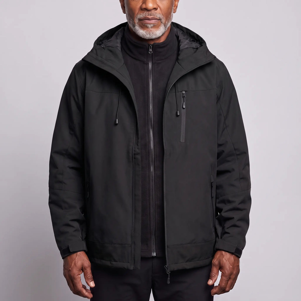 Men's black waterproof hooded hiking jacket worn open over a black zip-in fleece