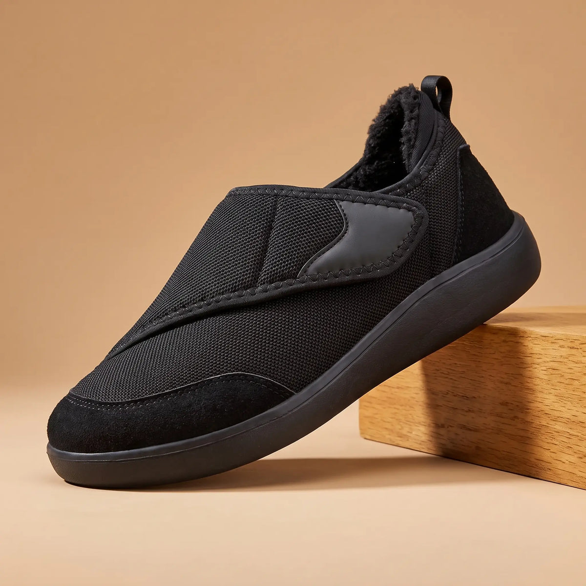 Men's black warm lined strap slip-on shoe on an oak block