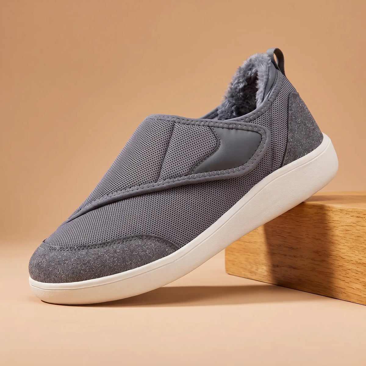 Men's grey warm lined strap slip-on shoe with white sole on an oak block