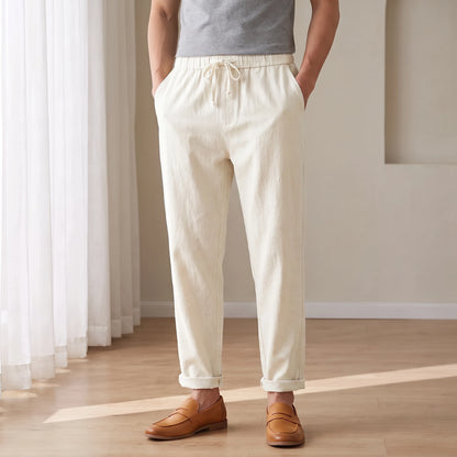 Drawstring cotton linen trousers in white, worn in a bright airy room