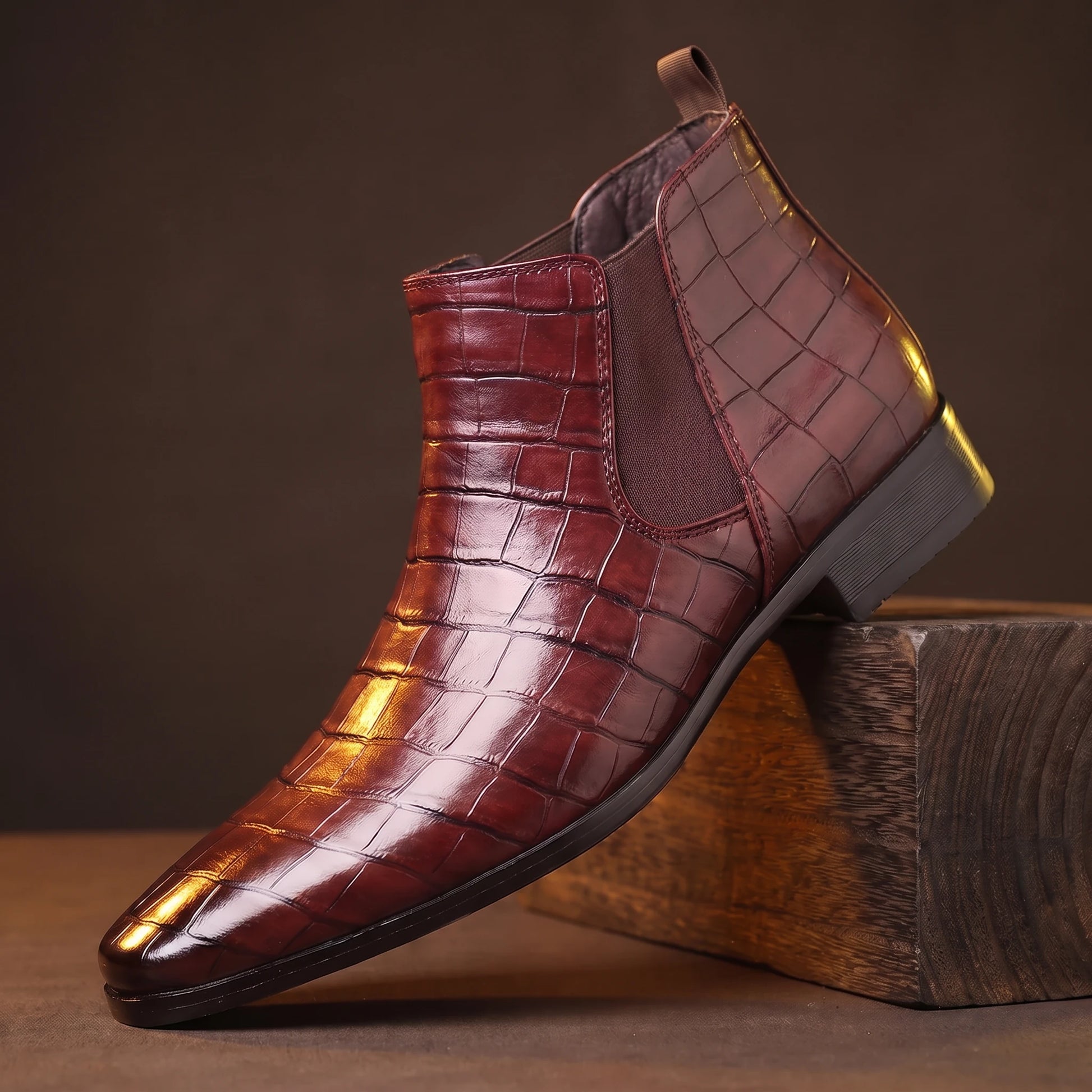 CROC GRAIN BOOTS wine-red croc-texture platform Chelsea boot on a smoked-oak block, moody amber light