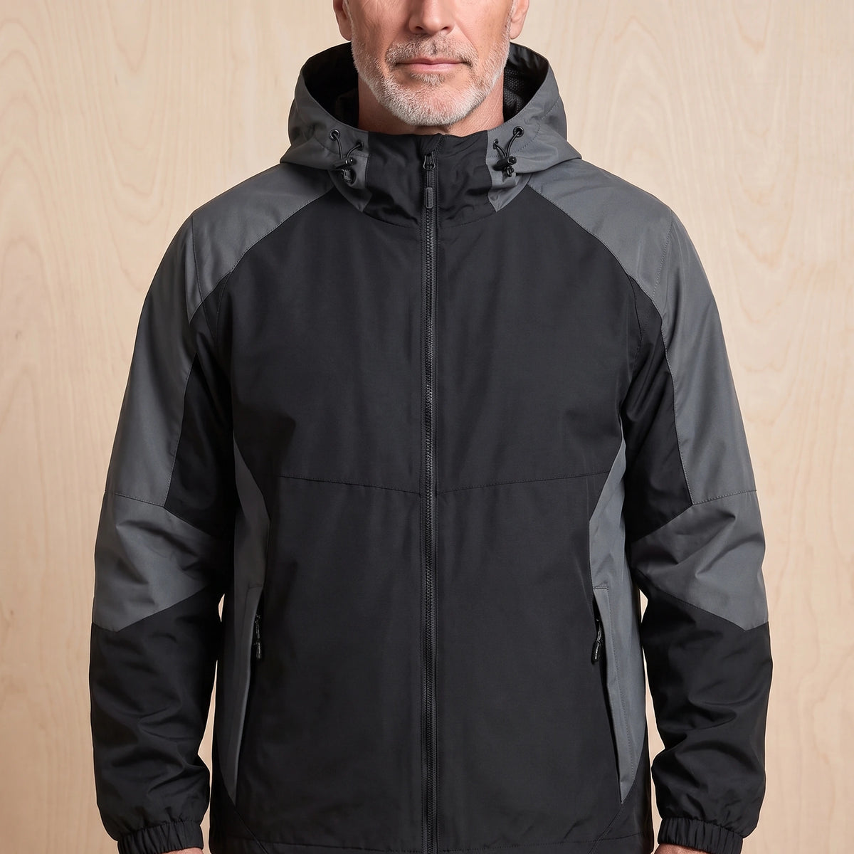 Black hooded panel windbreaker with grey colour block sleeves worn by a man, front view