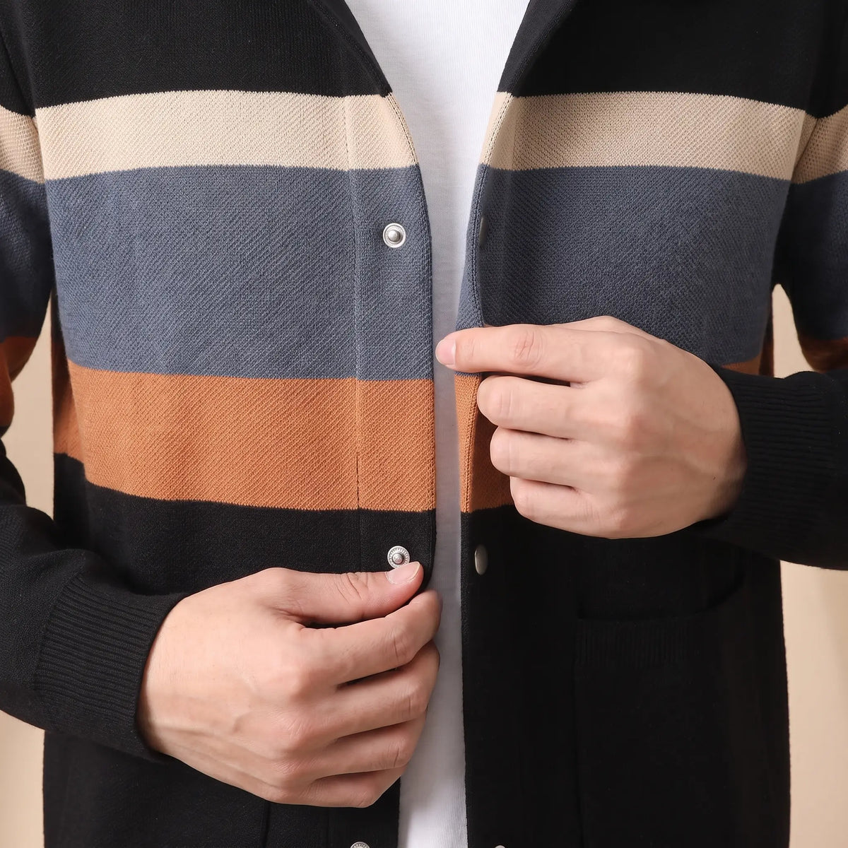 Man closing a snap button on the black orange Chest Band Knit worn over a white tee