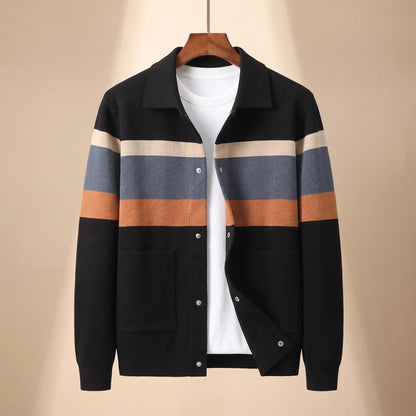 Chest Band Knit in black with orange chest bands, a colour blocked knit jacket with a turn down collar and snap placket on a wooden hanger