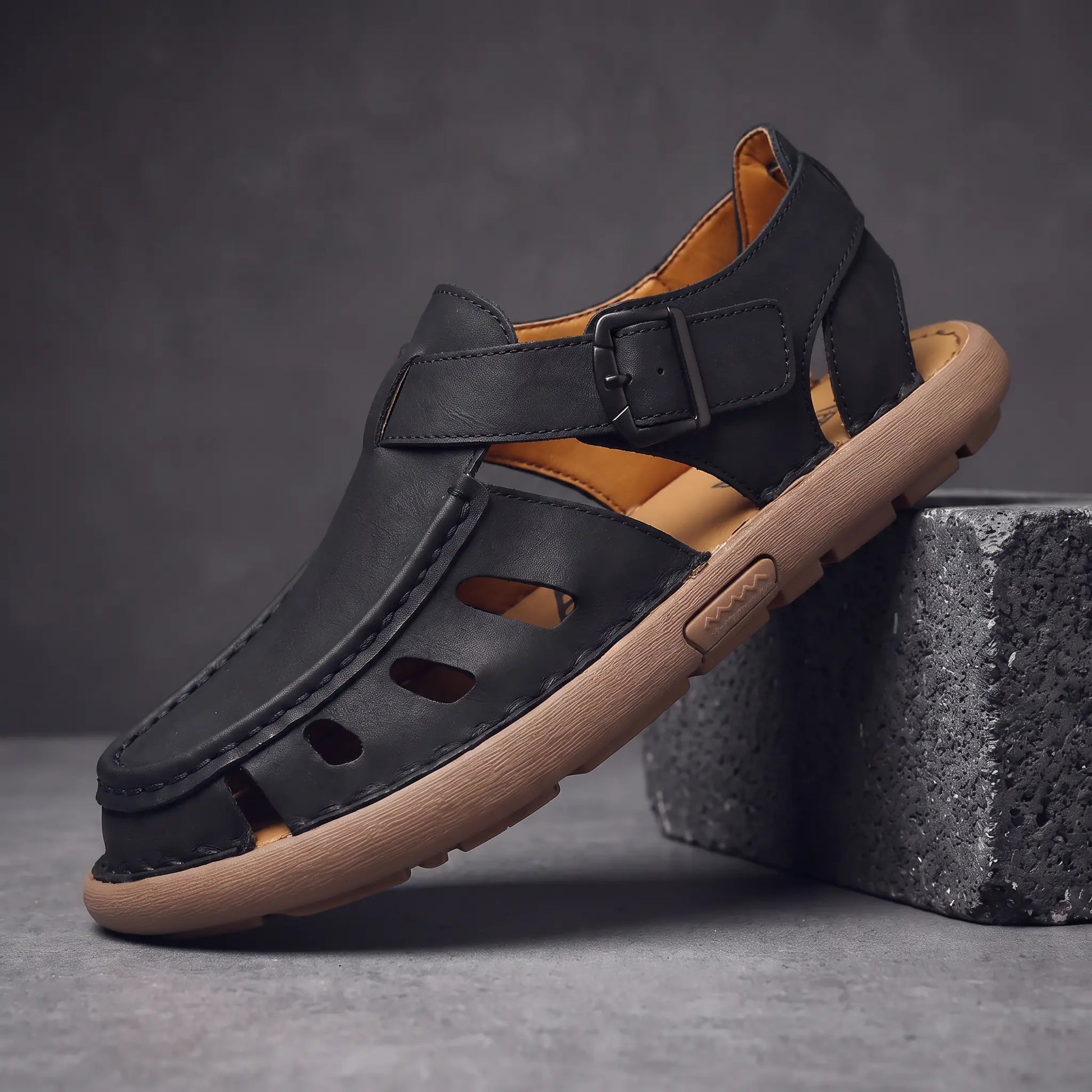 Black Roman leather sandal on charcoal block