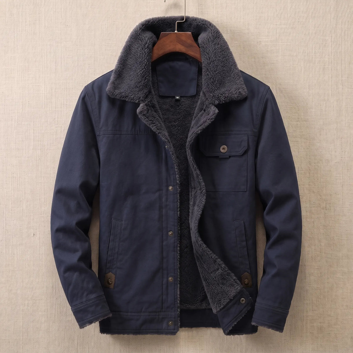 Navy cotton canvas sherpa lined jacket on a wooden hanger