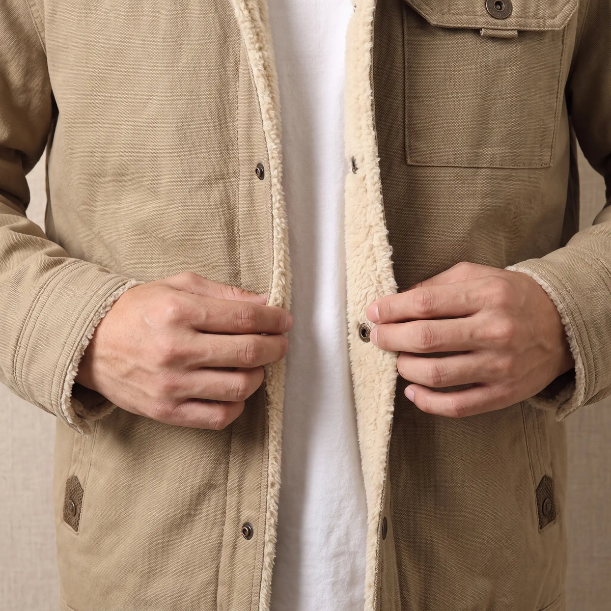 Man fastening the snap front of the canvas jacket