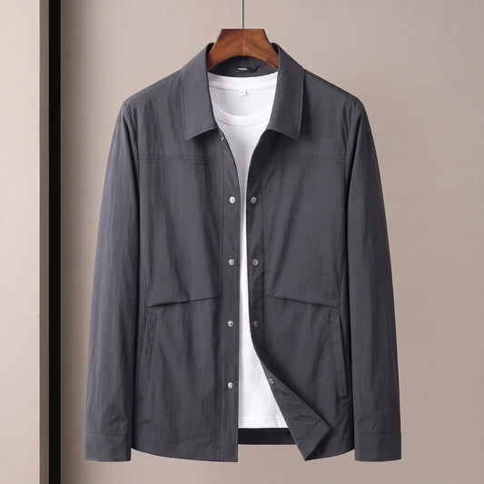 Crease Free Jacket in dark grey, a lightweight woven shirt jacket with a pointed collar, metal snap placket and welt hip pockets on a wooden hanger