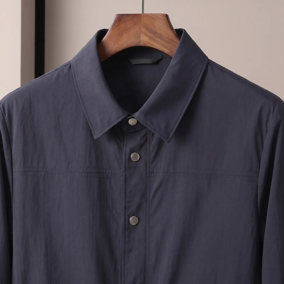Close up of the pointed collar and metal snap placket on the navy Crease Free Jacket