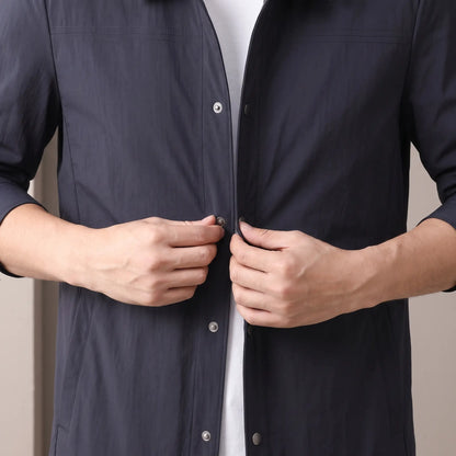 Man closing a metal snap on the navy Crease Free Jacket worn over a white tee